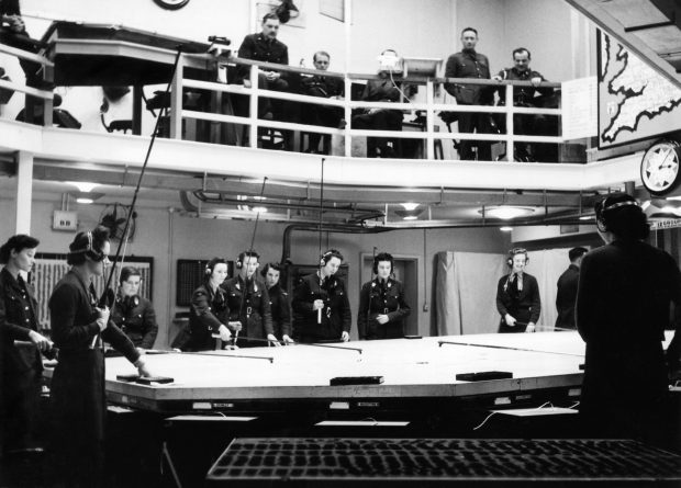 WAAF plotters at work in the underground Operations Room at HQ Fighter Command, Bentley Priory, in north-west London. A senior officer studies the unfolding events from the viewing deck above.