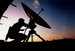 A soldier adjusts a satellite dish.