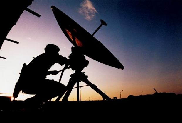 A soldier adjusts a satellite dish. Satellite communications provide a rear link between overseas deployments and the United Kingdom