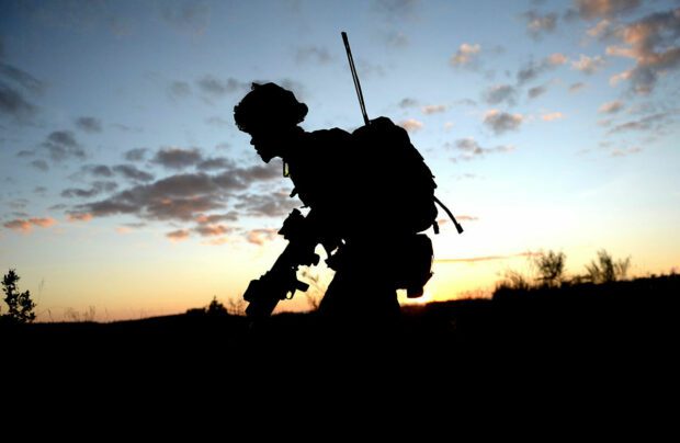 A silhouette of a soldier against a sunset sky