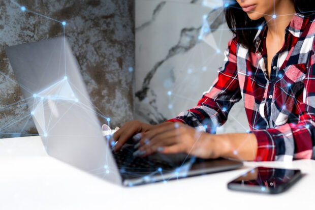 A woman sits at a laptop typing