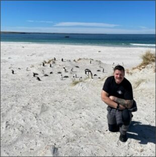 Joseph Washington on a beach with penguins